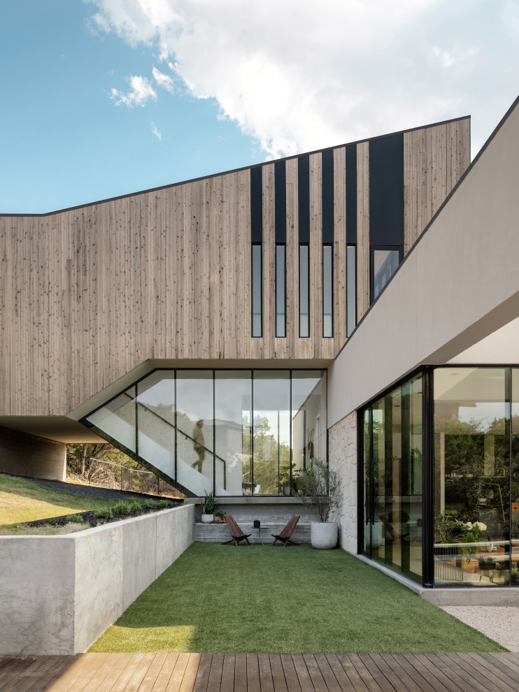 Large modern split-level house exterior in Austin with wood siding, a flat roof and a mixed roof.