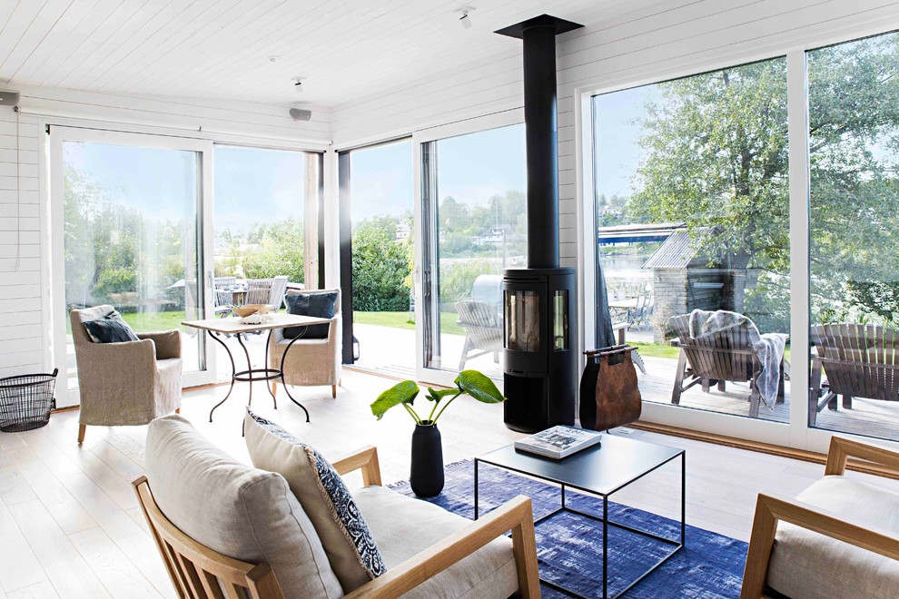 This is an example of a mid-sized scandinavian open concept living room in Stockholm with white walls, light hardwood floors, a standard fireplace and a metal fireplace surround.