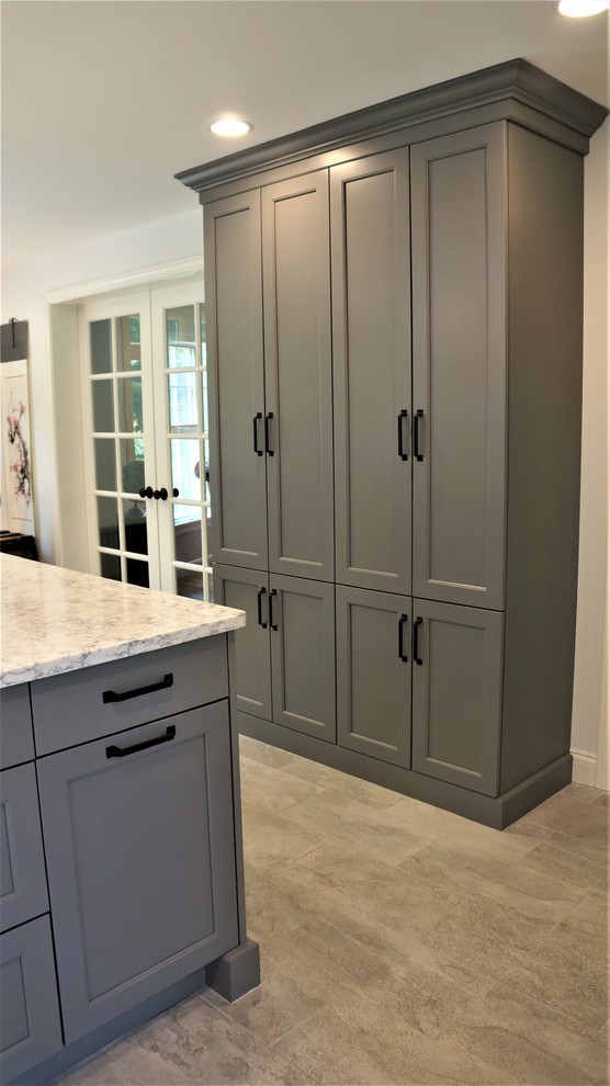 Example of a mid-sized transitional galley porcelain tile and gray floor open concept kitchen design in Boston with a farmhouse sink, recessed-panel cabinets, quartz countertops, white backsplash, porcelain backsplash, stainless steel appliances, an island and white countertops