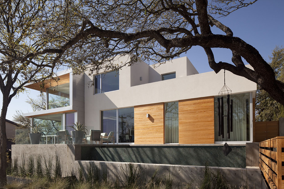 Design ideas for a large modern two-storey white exterior in Austin with wood siding and a flat roof.