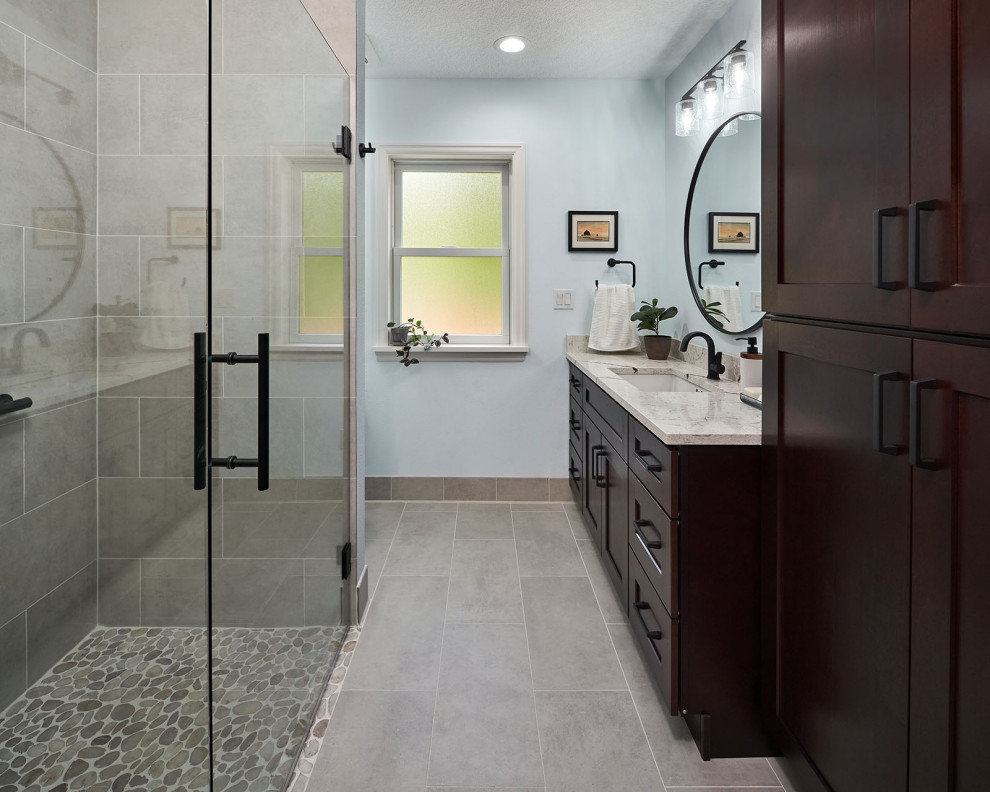 Klassisk inredning av ett mellanstort beige beige badrum med dusch, med skåp i shakerstil, bruna skåp, en kantlös dusch, grå kakel, porslinskakel, blå väggar, klinkergolv i porslin, ett undermonterad handfat, bänkskiva i kvarts, grått golv och dusch med gångjärnsdörr