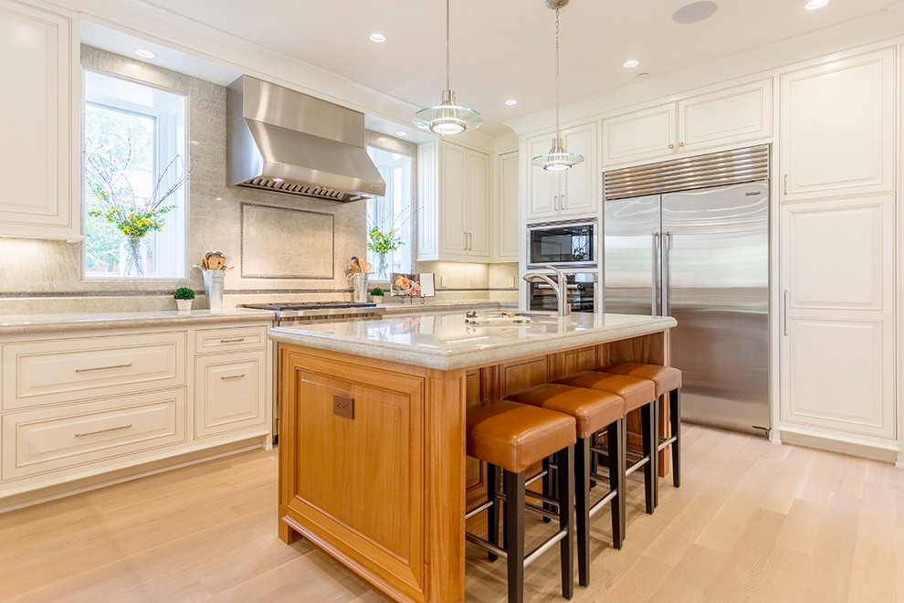 Photo of a traditional u-shaped kitchen in San Francisco with raised-panel cabinets, white cabinets, beige splashback, stainless steel appliances, light hardwood floors and with island.