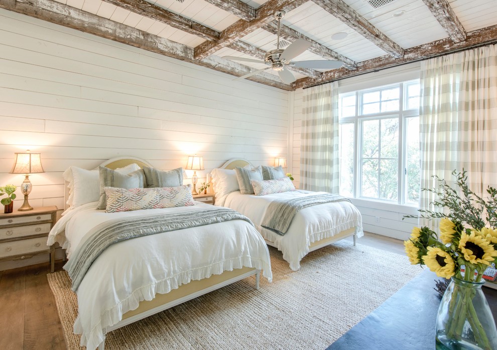 Photo of a large country guest bedroom in Austin with white walls and light hardwood floors.