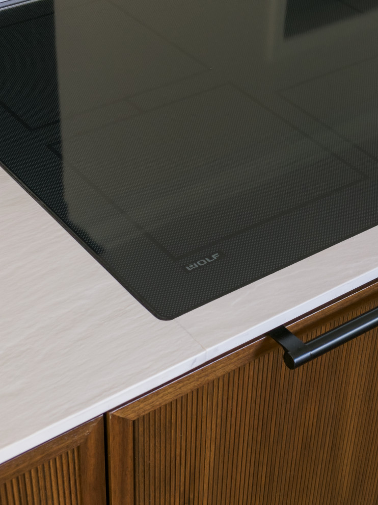 Example of a large transitional l-shaped medium tone wood floor and brown floor eat-in kitchen design in Chicago with an undermount sink, flat-panel cabinets, white cabinets, solid surface countertops, white backsplash, marble backsplash, paneled appliances, an island and black countertops