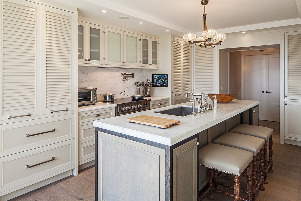This is an example of a transitional kitchen in Toronto with an undermount sink, louvered cabinets, white cabinets, white splashback and stainless steel appliances.