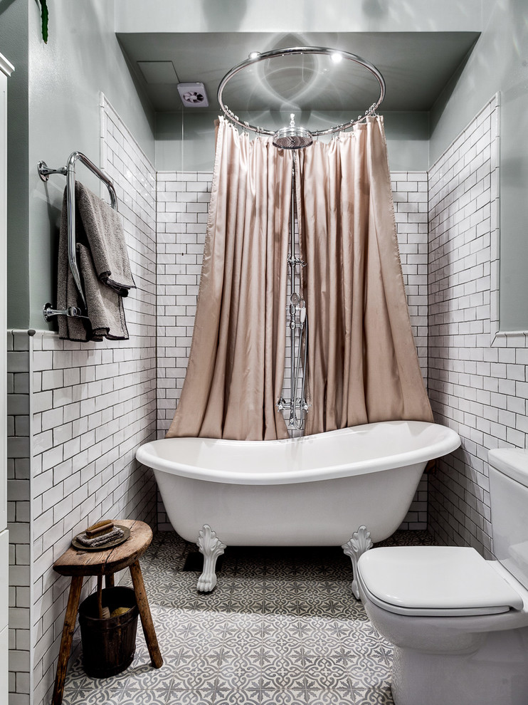 Mid-sized scandinavian bathroom in Stockholm with a claw-foot tub, a one-piece toilet, white tile, ceramic tile, white walls, ceramic floors and a shower curtain.