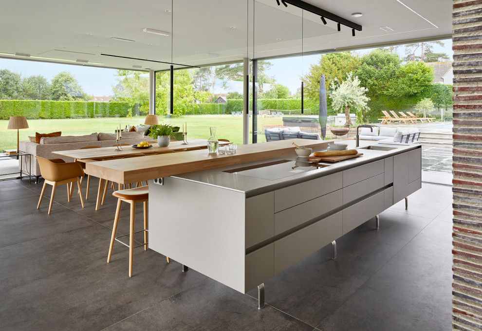 Exempel på ett stort modernt linjärt kök med öppen planlösning, med en integrerad diskho, släta luckor, grå skåp, bänkskiva i rostfritt stål, rostfria vitvaror och en köksö