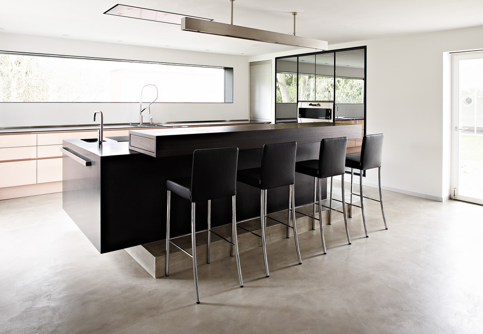 Photo of a modern eat-in kitchen in Other with flat-panel cabinets, concrete floors, with island, an integrated sink and white cabinets.