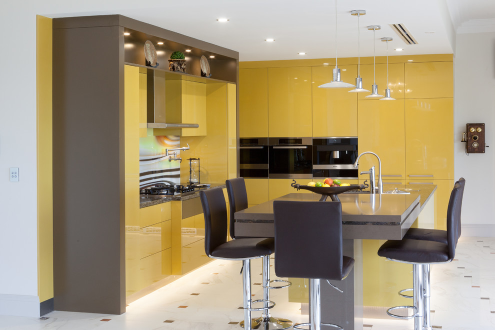 Inspiration for a modern l-shaped kitchen in Perth with flat-panel cabinets, yellow cabinets, granite benchtops, multi-coloured splashback, glass sheet splashback, stainless steel appliances, multiple islands and brown benchtop.
