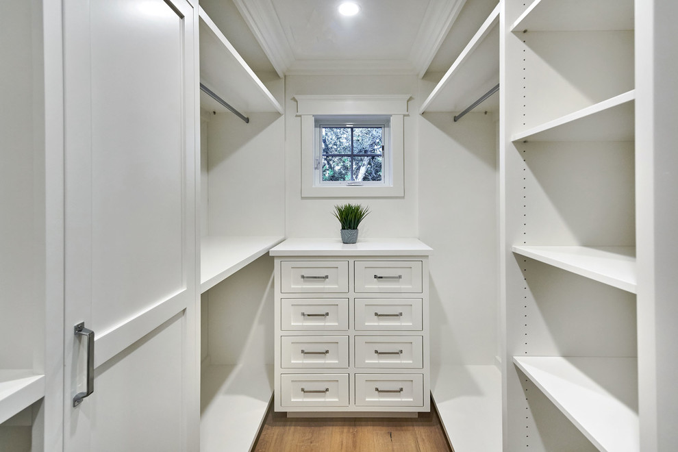 Photo of a small country gender-neutral walk-in wardrobe in San Francisco with shaker cabinets, white cabinets, light hardwood floors and grey floor.