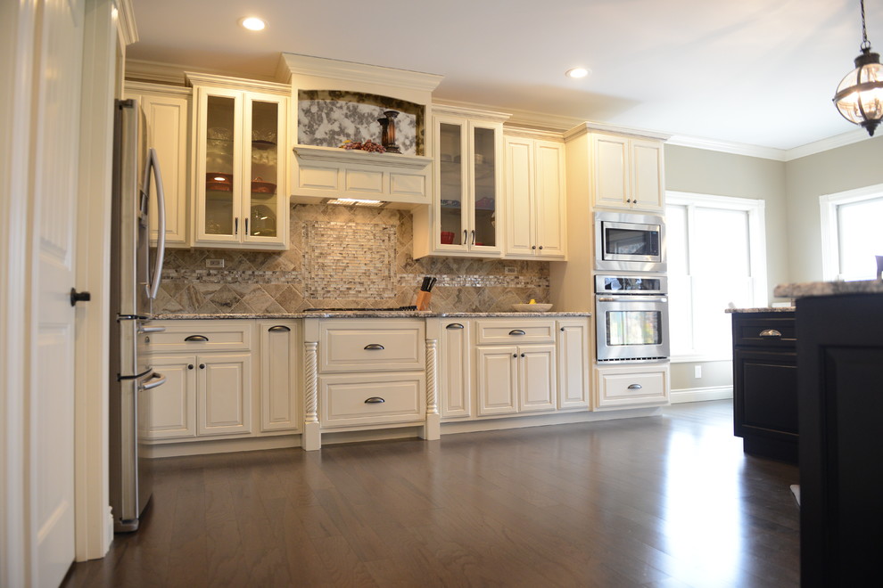 Inspiration for a transitional l-shaped medium tone wood floor eat-in kitchen remodel in Chicago with a farmhouse sink, raised-panel cabinets, white cabinets, granite countertops, gray backsplash, glass tile backsplash, stainless steel appliances and an island