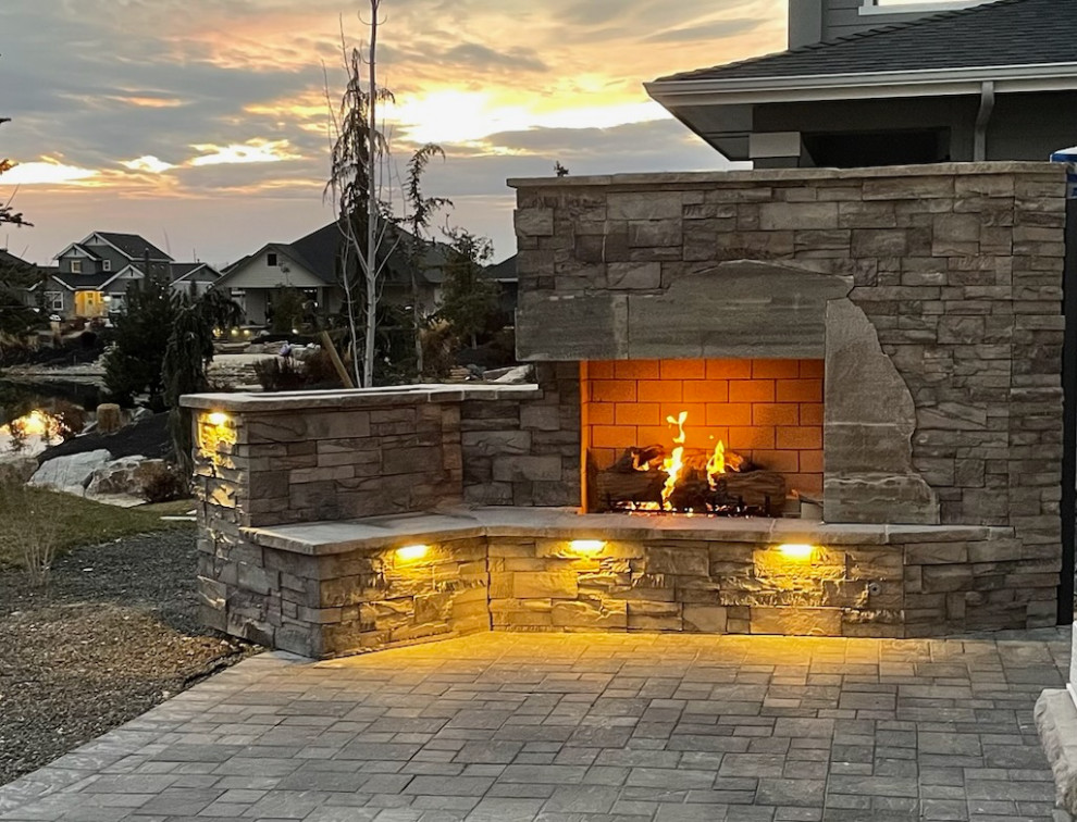 This is an example of a medium sized modern back patio in Boise with a fireplace, natural stone paving and no cover.