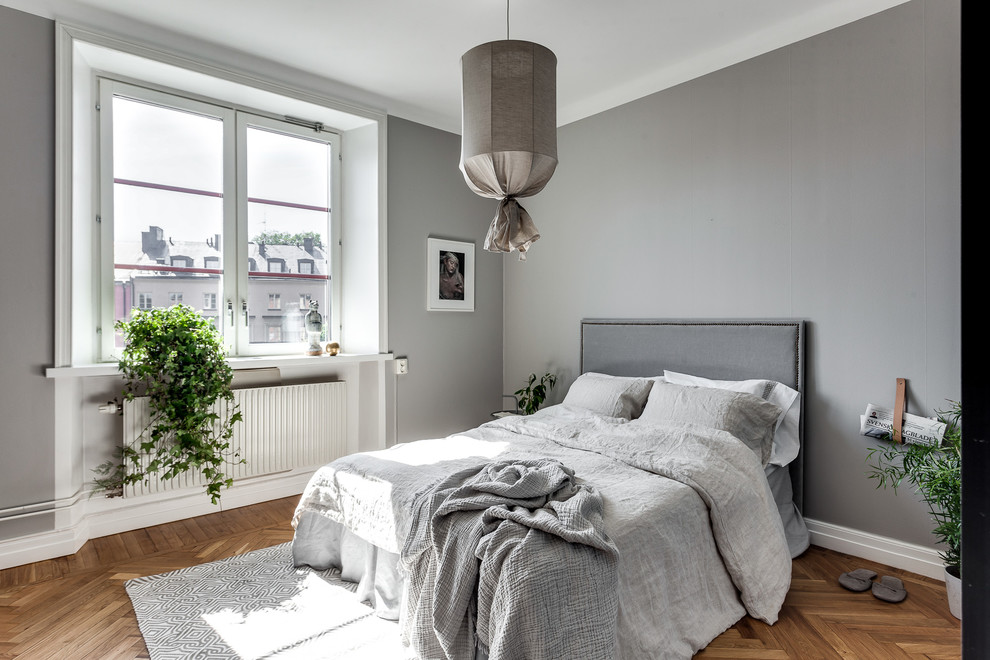 Mid-sized scandinavian master bedroom in Stockholm with grey walls, light hardwood floors and no fireplace.