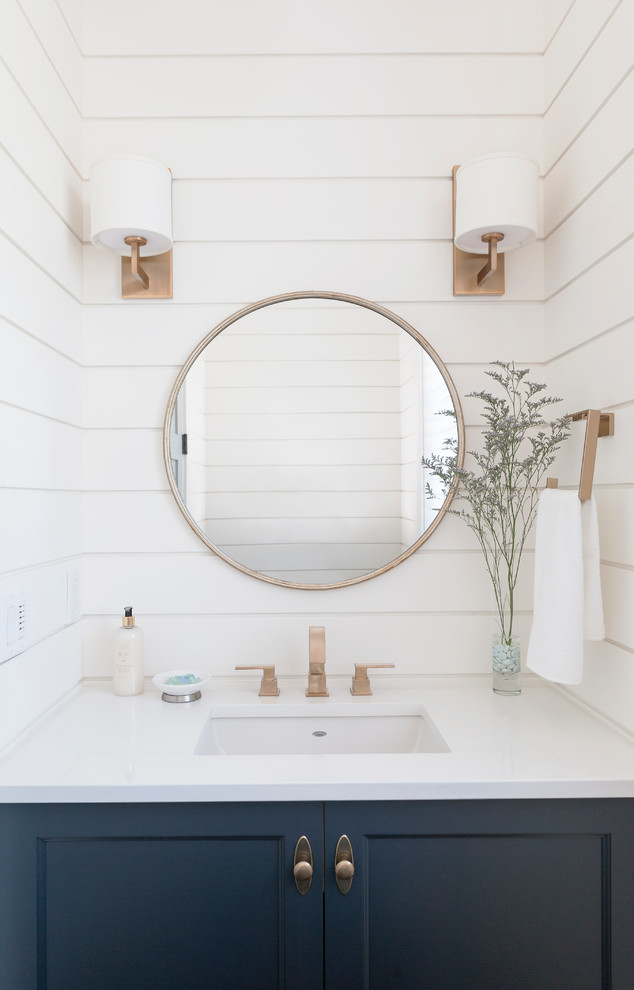 Photo of a beach style powder room in Vancouver with shaker cabinets, white walls and an undermount sink.