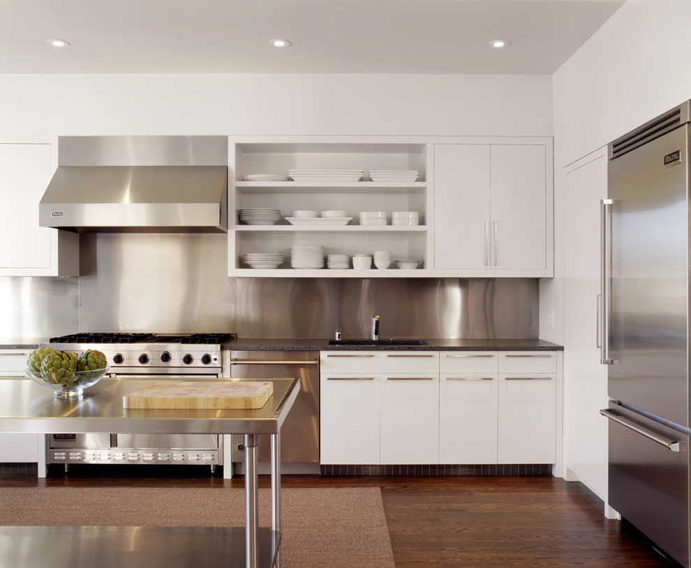 Modern l-shaped kitchen in San Francisco with stainless steel appliances, stainless steel benchtops, open cabinets, white cabinets, metallic splashback and metal splashback.
