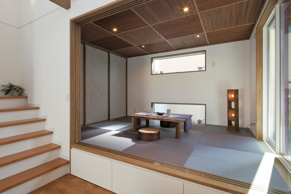 Photo of an asian enclosed family room with white walls, tatami floors and grey floor.