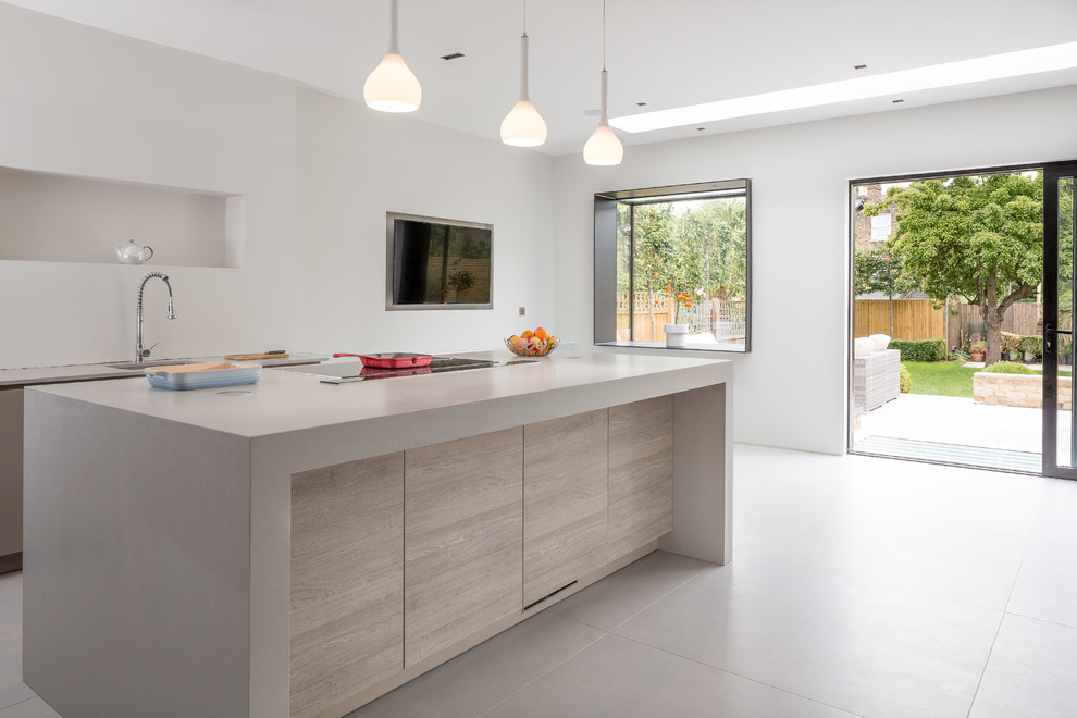 Expansive contemporary open plan kitchen in London with an integrated sink, flat-panel cabinets, grey cabinets, concrete benchtops, white splashback, stainless steel appliances, porcelain floors and with island.