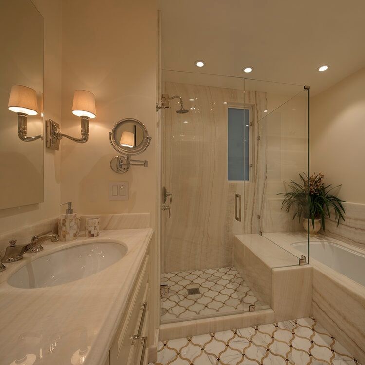Design ideas for a mid-sized transitional master bathroom in Denver with recessed-panel cabinets, beige cabinets, an undermount tub, a shower/bathtub combo, a wall-mount toilet, beige tile, stone slab, beige walls, mosaic tile floors, an undermount sink, onyx benchtops, beige floor and a hinged shower door.