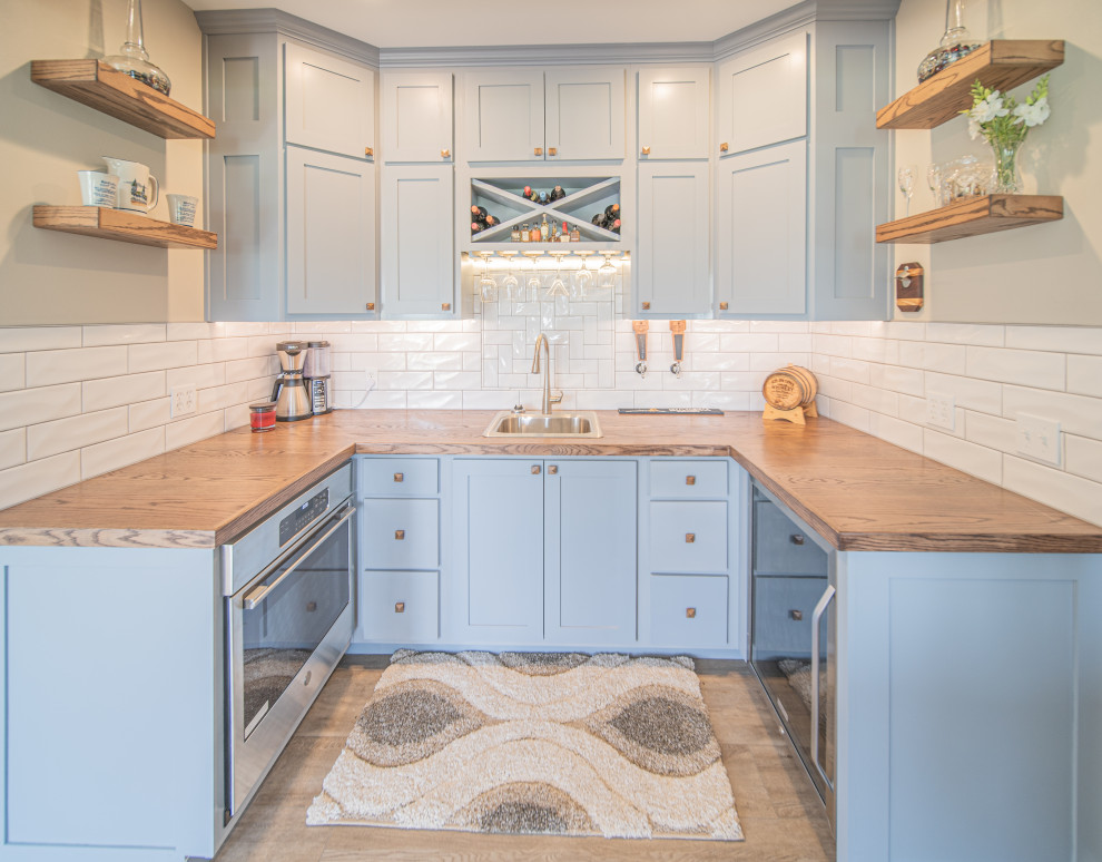 Small arts and crafts u-shaped wet bar in St Louis with a drop-in sink, shaker cabinets, grey cabinets, wood benchtops, ceramic splashback, vinyl floors and brown floor.
