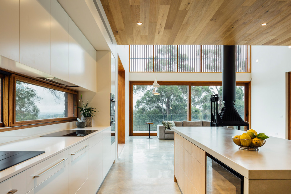 Inspiration for a large contemporary single-wall eat-in kitchen in Melbourne with a drop-in sink, flat-panel cabinets, light wood cabinets, concrete benchtops, concrete floors and with island.