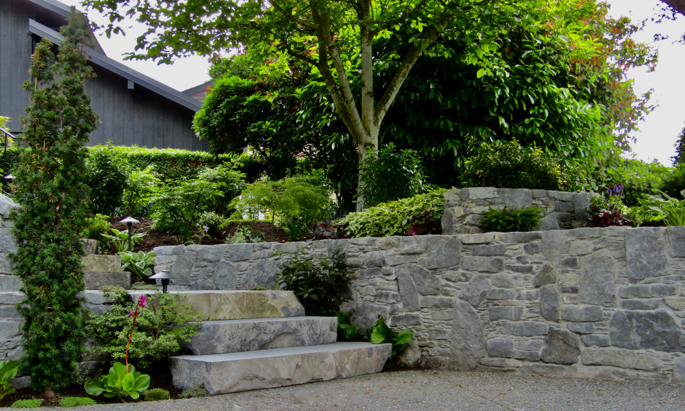 Foto di un giardino costiero esposto a mezz'ombra davanti casa con un muro di contenimento e pavimentazioni in pietra naturale
