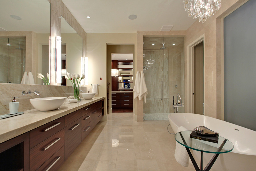 Photo of a large modern master bathroom in Calgary with a vessel sink, flat-panel cabinets, medium wood cabinets, granite benchtops, a freestanding tub, a curbless shower, a one-piece toilet, beige tile, stone tile, beige walls and ceramic floors.