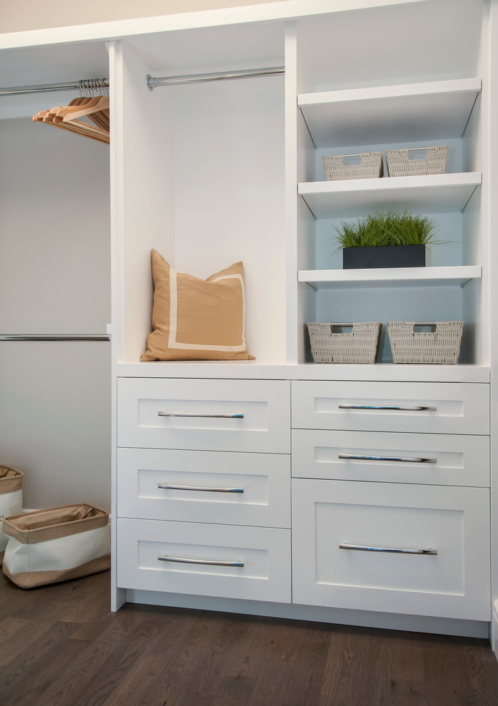 This is an example of a mid-sized contemporary gender-neutral walk-in wardrobe in Calgary with shaker cabinets, white cabinets and dark hardwood floors.