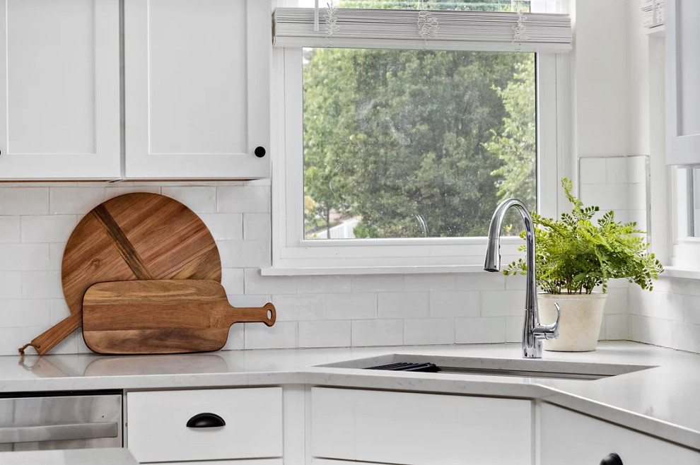Example of a mid-sized transitional u-shaped ceramic tile and beige floor eat-in kitchen design with a drop-in sink, recessed-panel cabinets, white cabinets, quartzite countertops, white backsplash, ceramic backsplash, stainless steel appliances, an island and white countertops