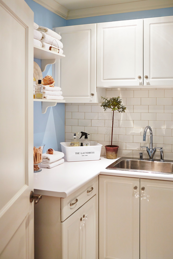 This is an example of a small beach style utility room in Toronto with a drop-in sink, raised-panel cabinets, white cabinets, laminate benchtops, blue walls, ceramic floors and a side-by-side washer and dryer.