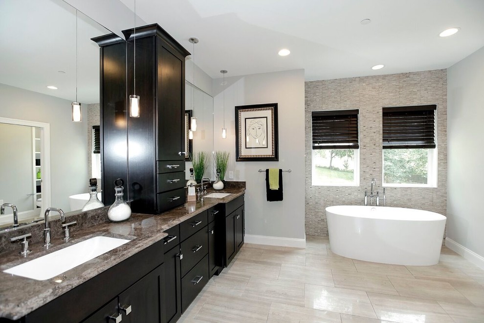 Inspiration for a mid-sized transitional master bathroom in DC Metro with shaker cabinets, black cabinets, a freestanding tub, a one-piece toilet, grey walls, limestone floors, an undermount sink and granite benchtops.