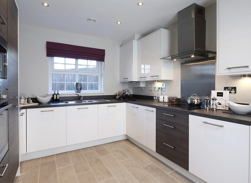 Small contemporary u-shaped eat-in kitchen in Cheshire with a double-bowl sink, flat-panel cabinets, white cabinets, solid surface benchtops, metallic splashback, metal splashback, stainless steel appliances, porcelain floors, no island, beige floor and grey benchtop.