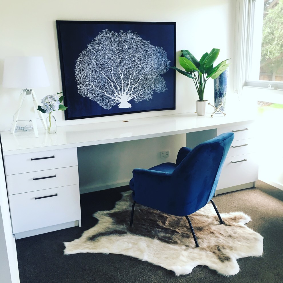 This is an example of a mid-sized beach style home office in Melbourne with white walls, carpet and a built-in desk.