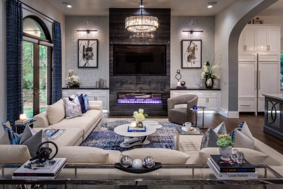 Design ideas for an expansive traditional open plan games room in Houston with grey walls, medium hardwood flooring, a hanging fireplace, a metal fireplace surround, a wall mounted tv, brown floors and wallpapered walls.