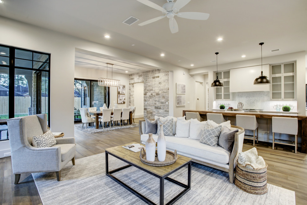 Example of a huge trendy open concept medium tone wood floor and brown floor family room design in Houston with white walls, a standard fireplace and a stacked stone fireplace