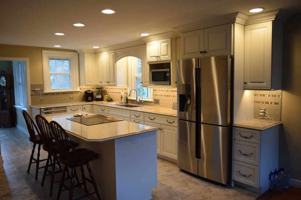 Inspiration for a mid-sized transitional l-shaped ceramic tile kitchen remodel with an undermount sink, raised-panel cabinets, yellow cabinets, quartz countertops, gray backsplash, subway tile backsplash, stainless steel appliances and an island
