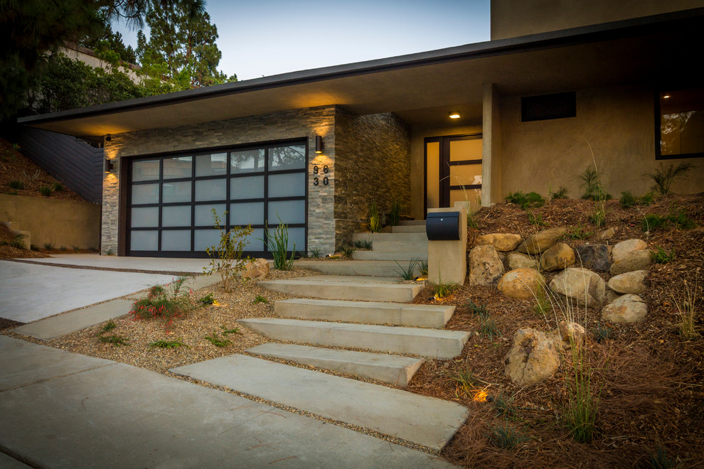 This is an example of a large midcentury front door in Los Angeles with beige walls, concrete floors, a single front door and a glass front door.