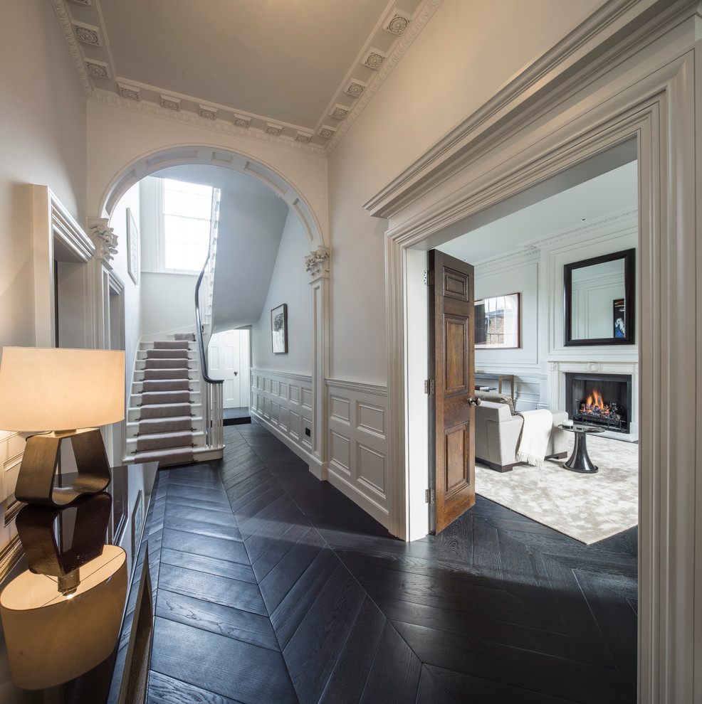 Photo of a large traditional entry hall in London with white walls and dark hardwood floors.