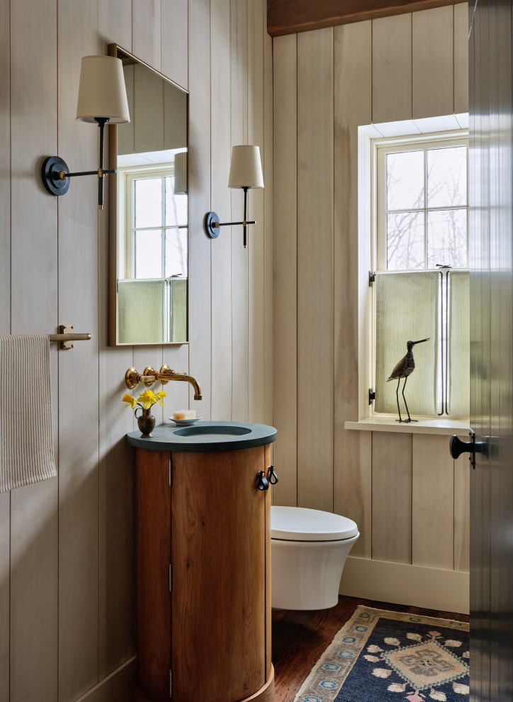Example of a farmhouse dark wood floor, brown floor and wood wall powder room design in Burlington with flat-panel cabinets, medium tone wood cabinets, a wall-mount toilet, beige walls, an undermount sink, blue countertops and a freestanding vanity