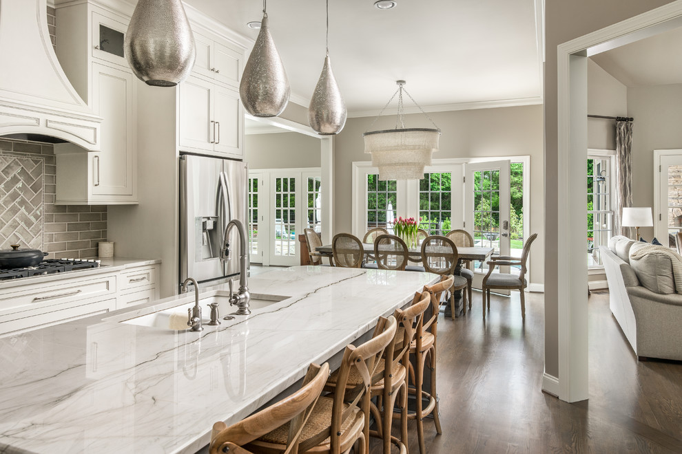 Transitional open plan kitchen in Nashville with white cabinets, with island, a double-bowl sink, beaded inset cabinets, grey splashback, stainless steel appliances, medium hardwood floors and brown floor.