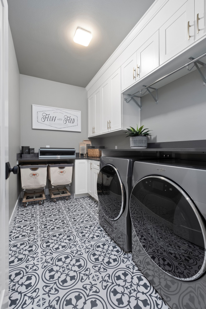 Transitional l-shaped dedicated laundry room in Other with shaker cabinets, white cabinets, grey walls, a side-by-side washer and dryer, multi-coloured floor and grey benchtop.