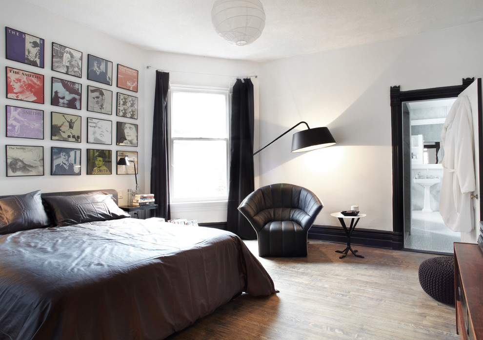 This is an example of a contemporary bedroom in Toronto with white walls, medium hardwood floors and no fireplace.