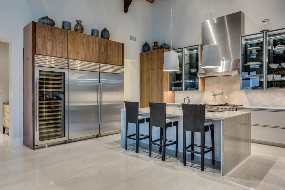 Design ideas for an expansive contemporary u-shaped open plan kitchen in Austin with glass-front cabinets, grey cabinets, stainless steel appliances, with island, a drop-in sink and white splashback.