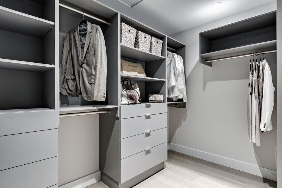 Inspiration for a contemporary walk-in wardrobe in Vancouver with flat-panel cabinets, grey cabinets and light hardwood floors.
