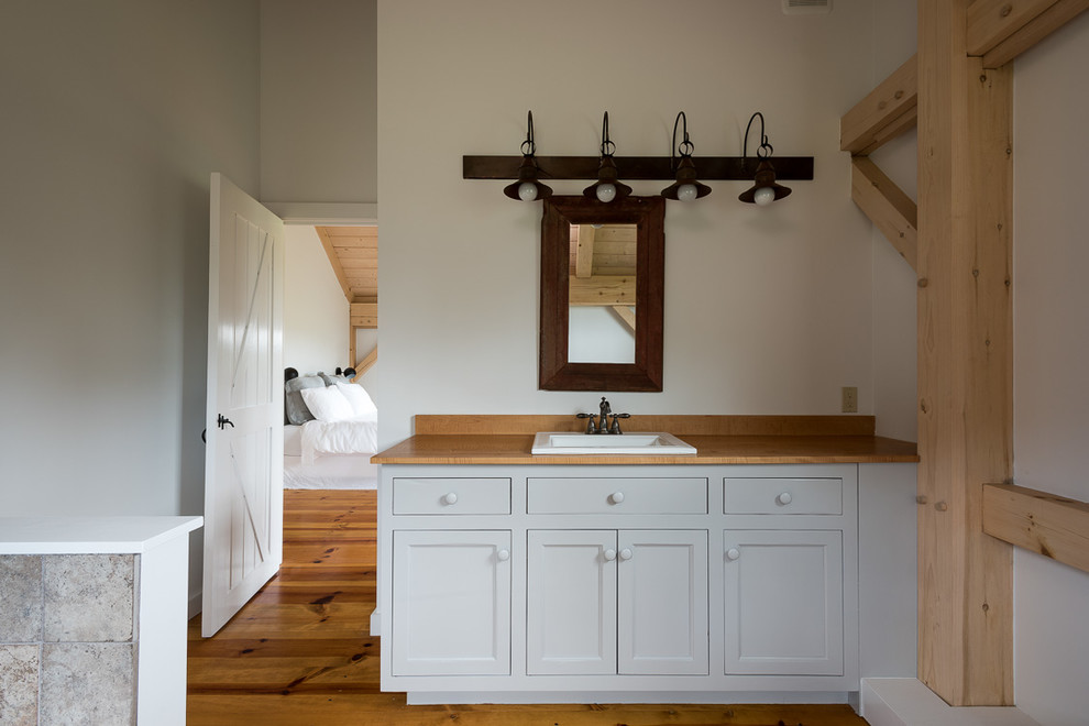 Mid-sized country master bathroom in New York with recessed-panel cabinets, white cabinets, white walls, light hardwood floors, wood benchtops and yellow floor.