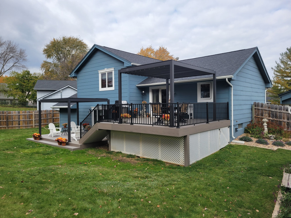 Example of a large backyard ground level metal railing deck design with a pergola