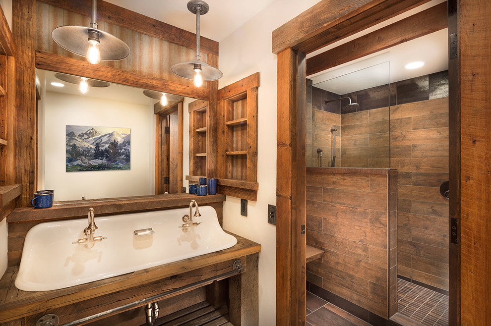 This is an example of a mid-sized country kids bathroom in Other with open cabinets, medium wood cabinets, an alcove shower, a wall-mount toilet, brown tile, porcelain tile, beige walls, medium hardwood floors, a wall-mount sink and wood benchtops.