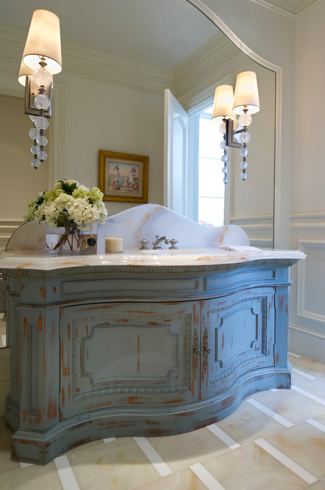 This is an example of an expansive traditional powder room in Miami with furniture-like cabinets, distressed cabinets, an undermount sink, onyx benchtops and stone slab.