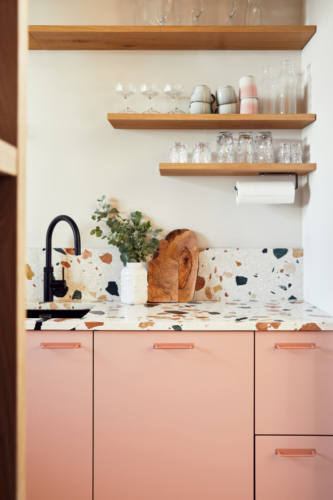 Immagine di una piccola cucina a L contemporanea chiusa con ante rosa, top alla veneziana, elettrodomestici neri, nessuna isola e top multicolore