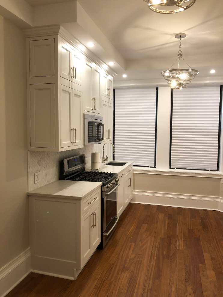 Small transitional galley dark wood floor and brown floor eat-in kitchen photo in New York with an undermount sink, recessed-panel cabinets, white cabinets, quartz countertops, multicolored backsplash, marble backsplash, paneled appliances, no island and white countertops