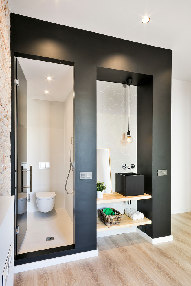 Inspiration for a small industrial powder room in Barcelona with open cabinets, light wood cabinets, a wall-mount toilet, black walls, wood benchtops, a vessel sink, beige floor and beige benchtops.
